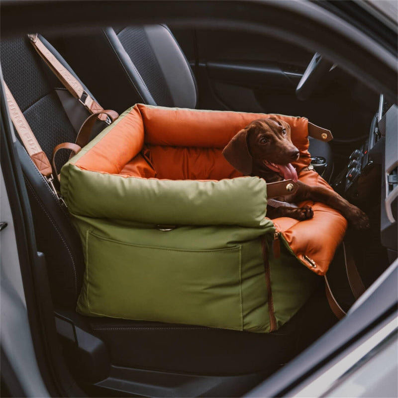 Dog lying on a green and orange pet seat in a car